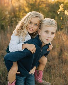 a boy and girl hugging each other in a field