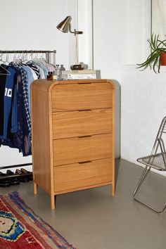 a wooden chest of drawers sitting next to a chair