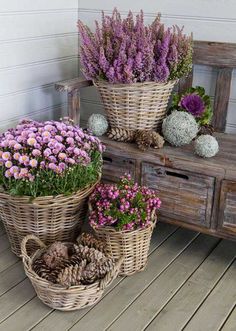 three baskets filled with flowers sitting on top of a wooden floor next to a bench