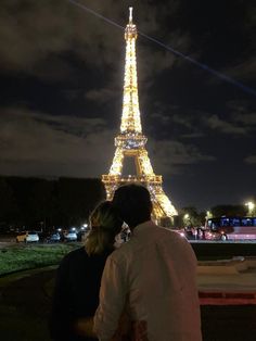 a man and woman sitting in front of the eiffel tower