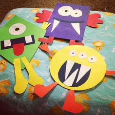 three paper cut out monsters sitting on top of a blue and green sheeted blanket