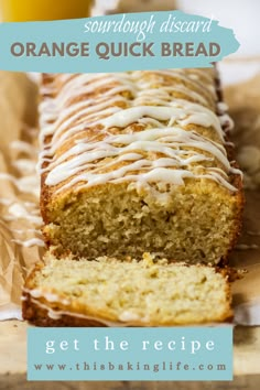 a close up of a loaf of bread with icing on it and a glass of orange juice in the background