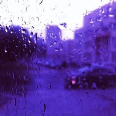 rain drops on a window as cars drive down the street