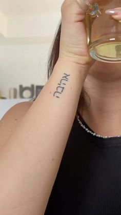 a woman with a tattoo on her arm holding a wine glass in front of her face