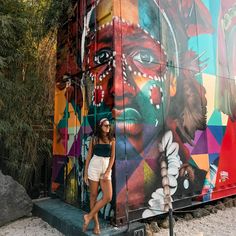 a woman is standing in front of a colorful wall with an image of a woman's face on it