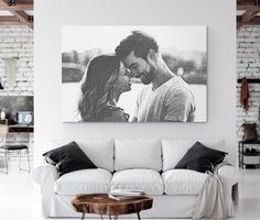 a black and white photo of a man and woman kissing on their foreheads in front of a brick wall