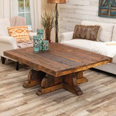 a living room with white couches and wooden table in the center, surrounded by wood flooring