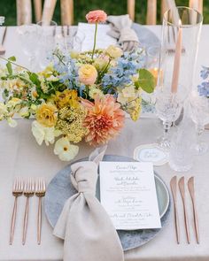 an image of a table setting with flowers and place settings on the table for dinner