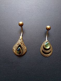 two pairs of gold earrings with mother's day stone in the center, on a black surface