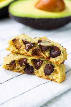 two chocolate chip cookies sitting on top of a towel next to an avocado