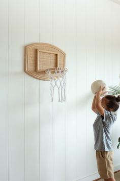 a young boy holding a frisbee in front of a wall mounted basketball hoop