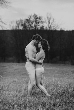 two people are hugging in the middle of a field