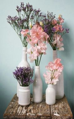 three white vases with pink flowers in them