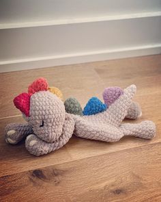 a crocheted stuffed animal laying on top of a hard wood floor next to a wall