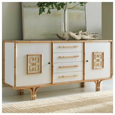 a white and gold sideboard with drawers on the bottom, two birds sitting on top of it