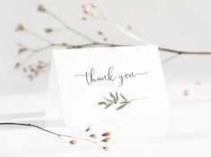 a thank you card sitting on top of a table next to some dried flowers and branches