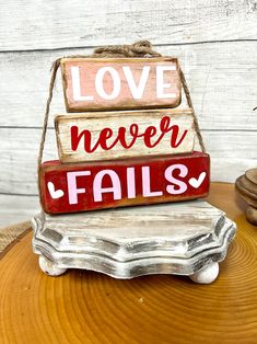 a wooden sign that says love never falls on top of a piece of drift wood