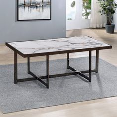 a marble top coffee table in a living room with grey carpet and potted plants