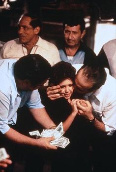 several people standing around each other with their faces covered by hands and money in front of them