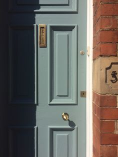 a blue door with a sign on it and a brick wall in the back ground