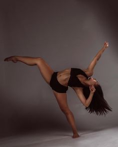 a woman in black shorts is doing a dance move with her legs spread out and one leg bent