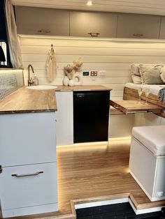 a kitchen with white cabinets and wood flooring next to a living room couches