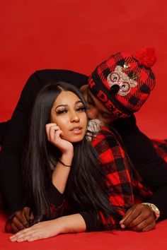 a woman laying on the ground next to a man wearing a red and black hat