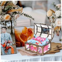 an open box sitting on top of a table next to pictures and flowers in vases