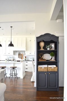 an open kitchen and dining room area with white cabinets, wood flooring and black accents