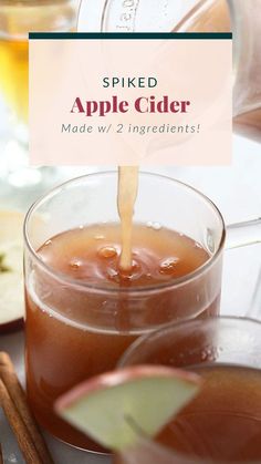 an apple cider being poured into a glass with cinnamon sticks and apples in the background