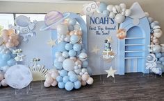 balloons and decorations are arranged on the floor in front of a wall that says noah's first birthday