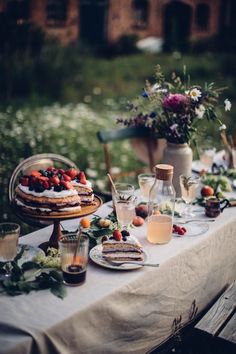 a table topped with cake and drinks on top of a wooden table covered in greenery