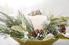 a candle and some pine cones in a bowl