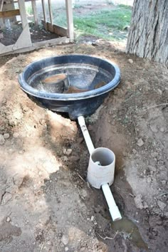 an old broken toilet bowl sitting on the ground in front of a tree and fence