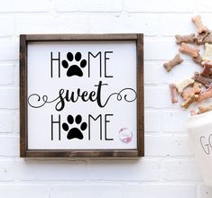 a sign that says home sweet home next to a cup of coffee and dog paw prints