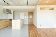 an empty kitchen with wood floors and white walls, along with wooden cabinetry on both sides