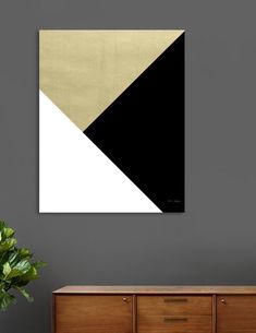 a black, white and gold abstract painting hangs on the wall above a wooden dresser