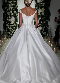 a woman in a white wedding dress with a mask on her head and flowers behind her