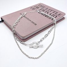 Double Strand Silver Tone Necklace With Front Toggle. This necklace is pictured laying on a pink book with a white background. Glamour Style, Giddy Up Glamour, Polished Look, Comfortable Fashion, Fashion Games, Silver Tone, Silver