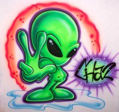 an alien is sitting on the ground in front of graffiti