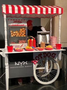 a man standing behind a food cart with hot dogs on the side and other foods