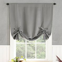 a kitchen window with a gray curtain and potted plant on the counter next to it