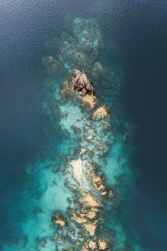 an aerial view of the ocean with rocks and corals on it's sides