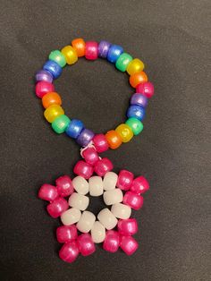 a multicolored beaded necklace on a black surface with white and pink beads