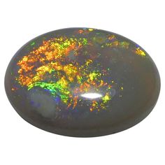 an oval shaped black opal with orange and green colors