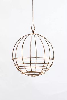 a metal ball hanging from a wire on a white background with the light shining through it