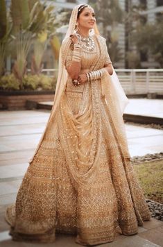 a woman in a gold and white wedding dress standing on the sidewalk with her arms around her neck