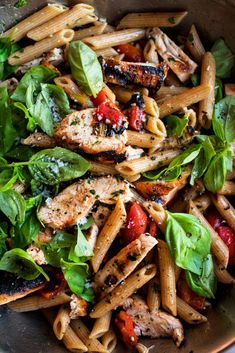 a bowl filled with pasta, chicken and spinach