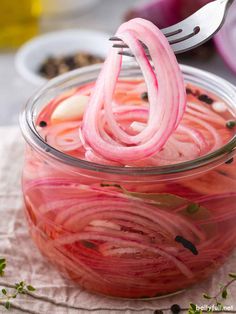 a jar filled with pickled onions sitting on top of a table next to a fork