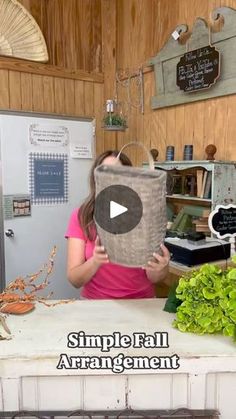 a woman standing in front of a kitchen counter holding up a bag that says simple fall arrangement